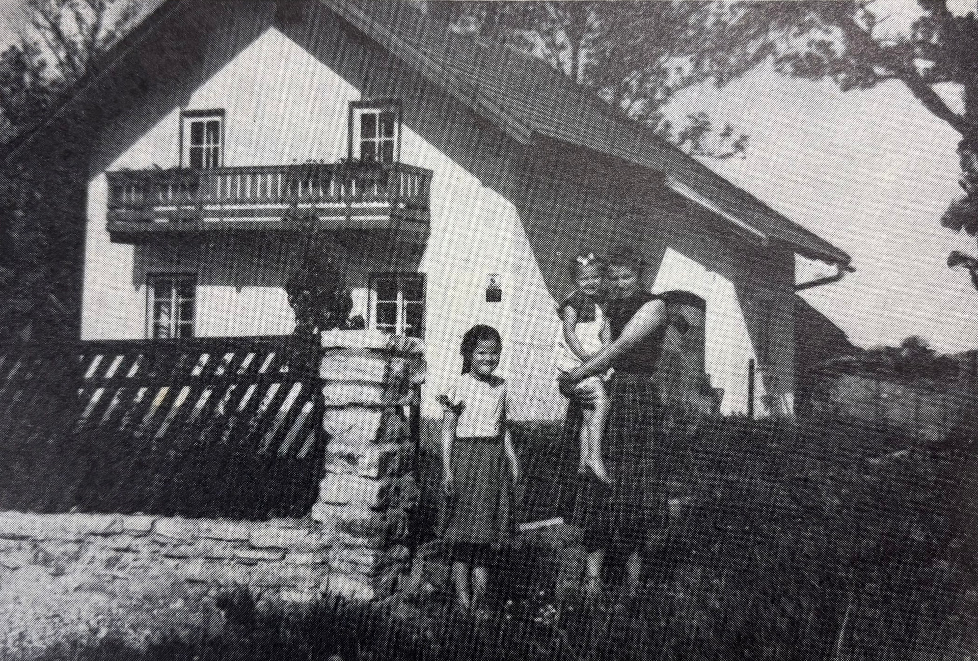 Mutter mit zwei Kindern vor ihrem Haus mit Garten